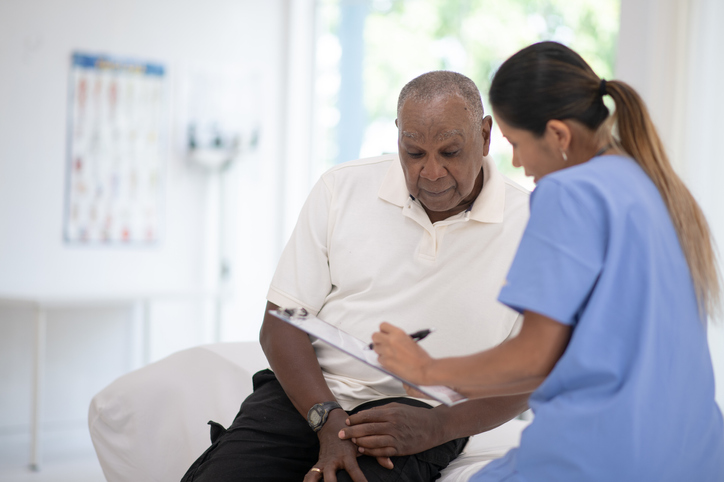 An African senior gentleman speaks with his doctor during a routine check-up in the doctors office